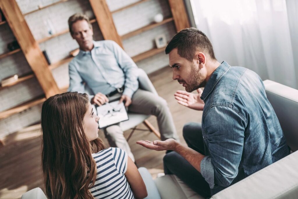 Three people, man arguing with woman while another man listens